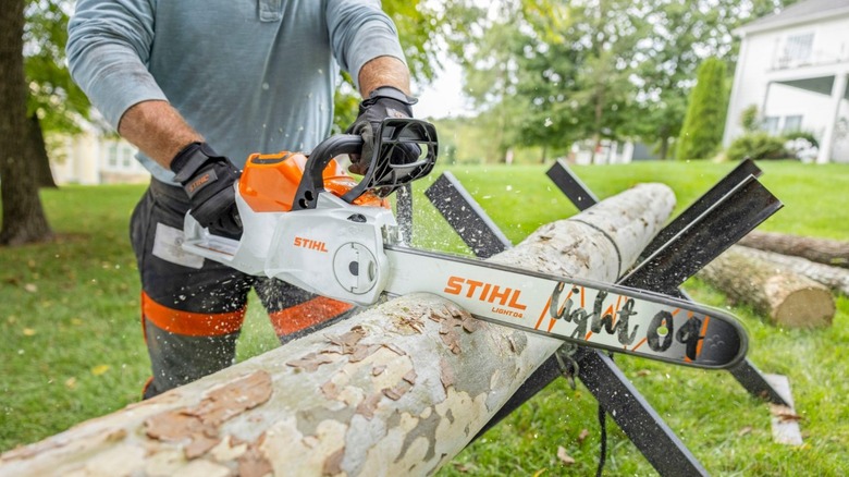 person using a Stihl MSA 200 chainsaw on a log