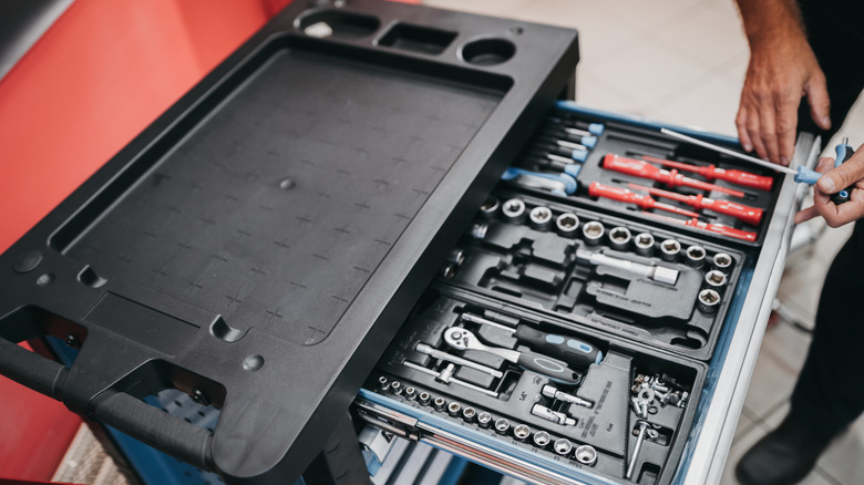A mechanic opening a drawer in a toolbox