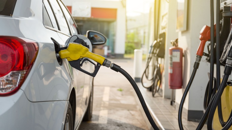A fuel nozzle inserted into a white car at a gas station
