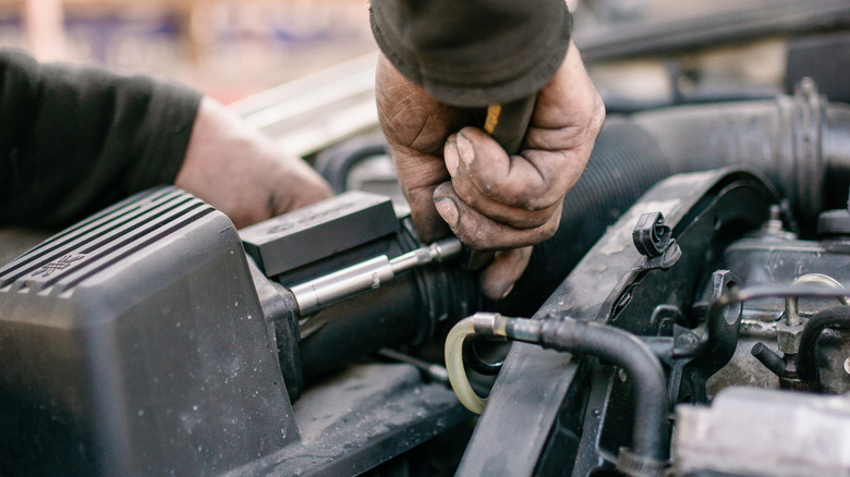 A car mechanic working on an old engine under the hood.