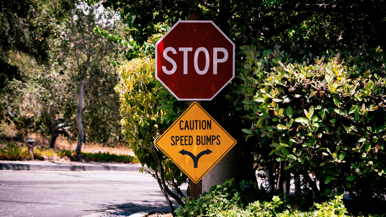 a stop sign with a Caution Speed Bumps warning sign below it