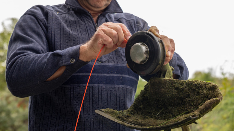Man restringing a trimmer line on string trimmer head.