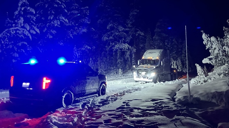 Police car in front of semi-truck stuck in snow
