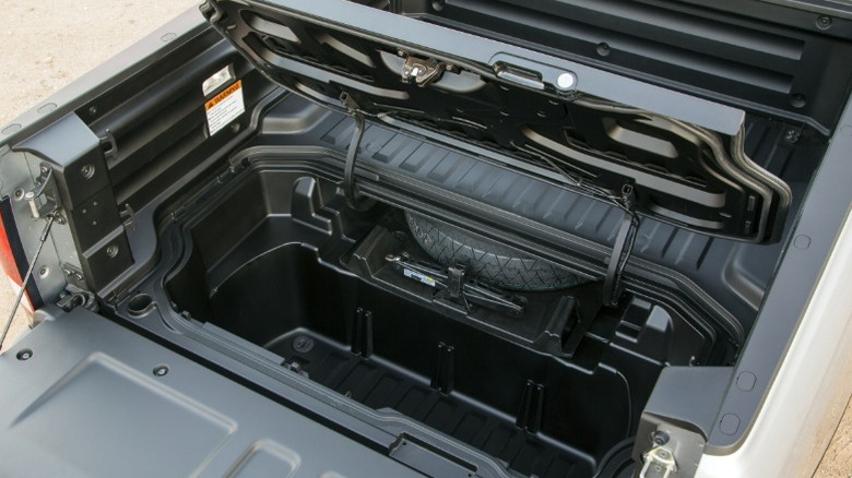 View of Honda Ridgeline rear cubby opened, showing spare tire