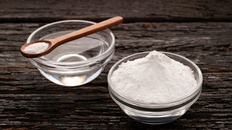 Baking soda and water in bowls with a wooden spoon