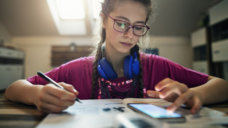 girl answering homework using phone