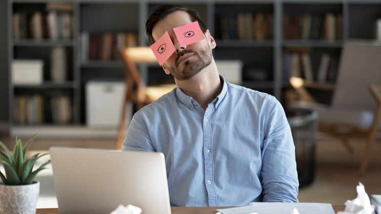 Man with eyes drawn on sticky notes pasted on face