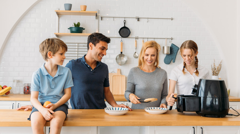 Boy, man, and two women in kitchen using air fryer