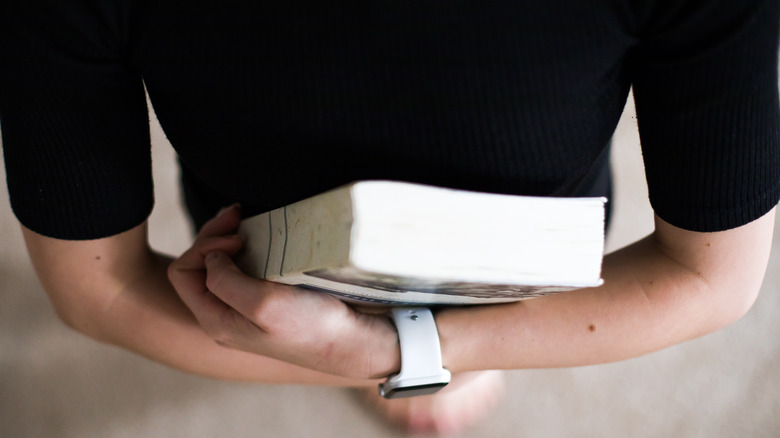 woman wearing apple watch and holding book