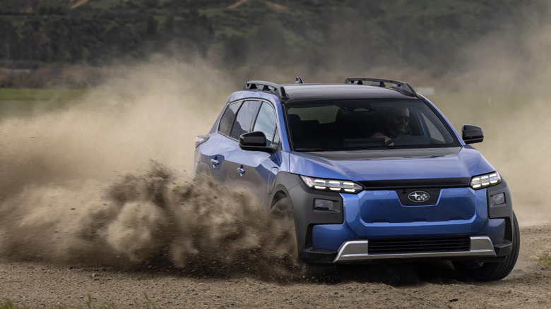 Blue Subaru Trailseeker kicking up dust on off-road trail.