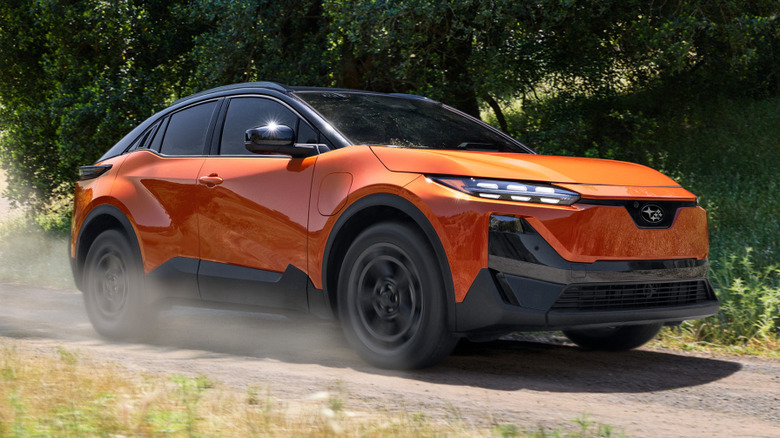 Front 3/4 view of Subaru Uncharted driving on dirt road in forested area