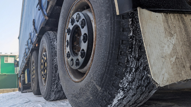 A semi-truck with a super single tire that's covered with ice