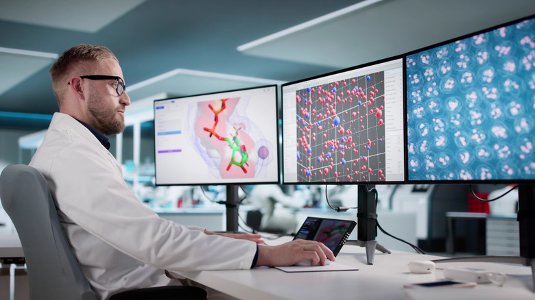 Man Analyzing Protein Structures On Multiple Computer Screens In Lab