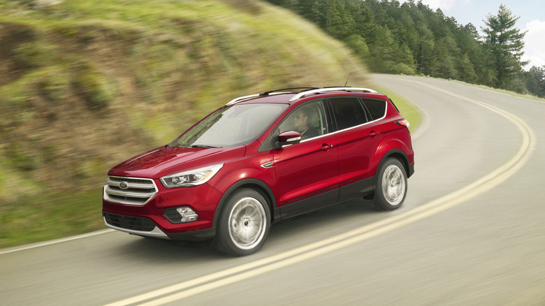 A red 2018 Ford Escape driving down a hilly road