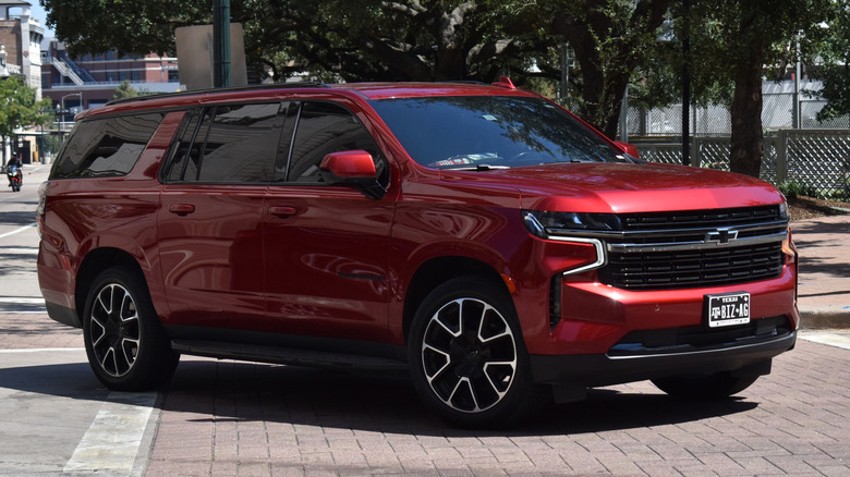 A red Chevrolet Tahoe sitting on a brick crosswalk on a public road