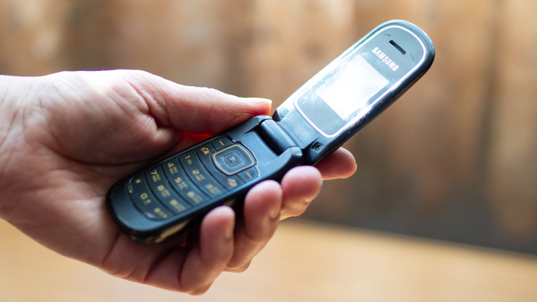 A close-up of a hand holding a flip phone