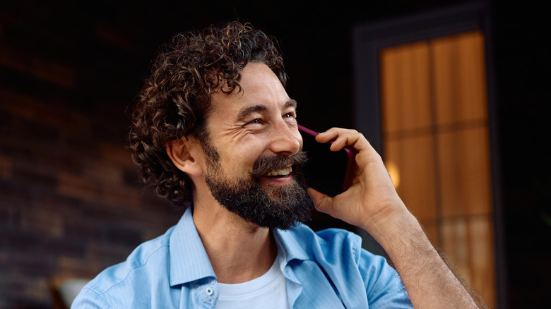 Smiling man using a smartphone held up to his ear
