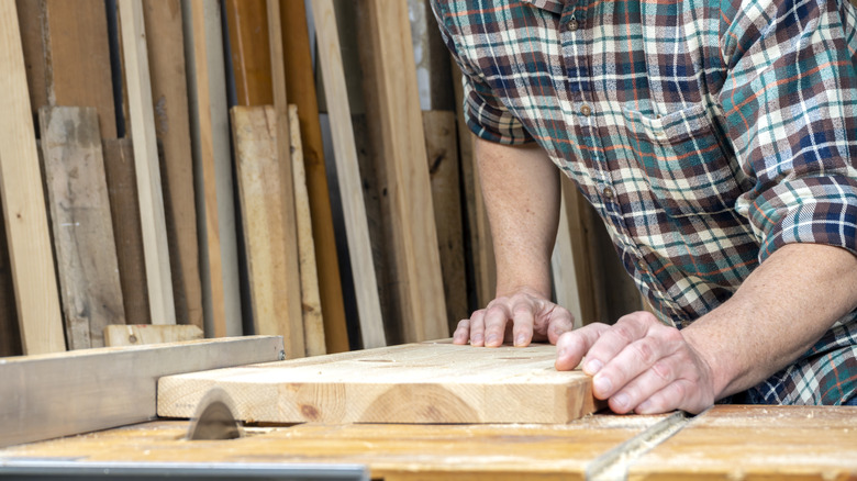 Carpenter using table saw to ripcut board