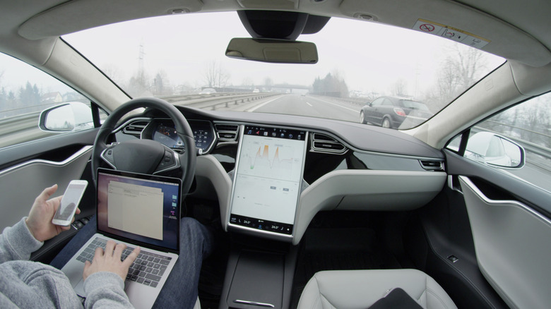 A person sitting in a self driving Tesla