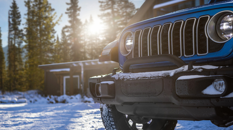 Front close-up shot of a Wrangler 4xe in a snowy landscape with a building in the background