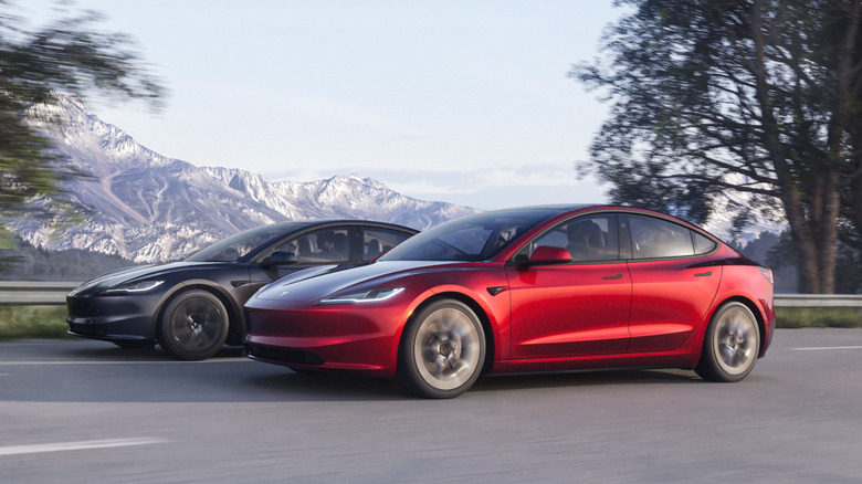 Two Tesla Model 3 Premium cars driving down highway side-by-side, left-side view