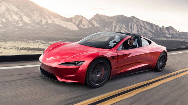 Front 3/4 view of red Tesla Roadster on mountain road.