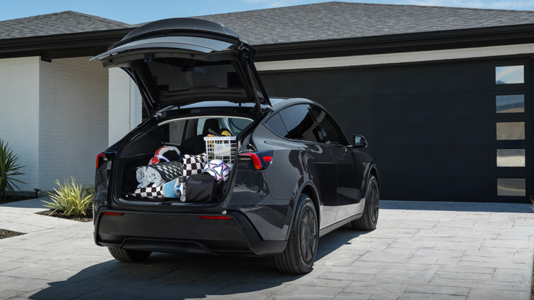 Black 2026 Tesla Model Y parked in front of a house with rear hatch open
