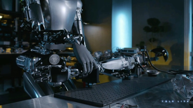Tesla bot grabbing a robot arm