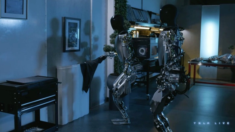 Two Tesla Bots looking at a photo of themselves at work
