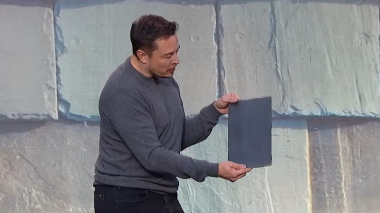 Elon Musk holding a Solar Roof tile at the 2016 launch of the Solar Roof