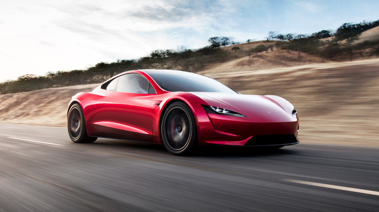 Red Tesla Roadster driving on a rural road
