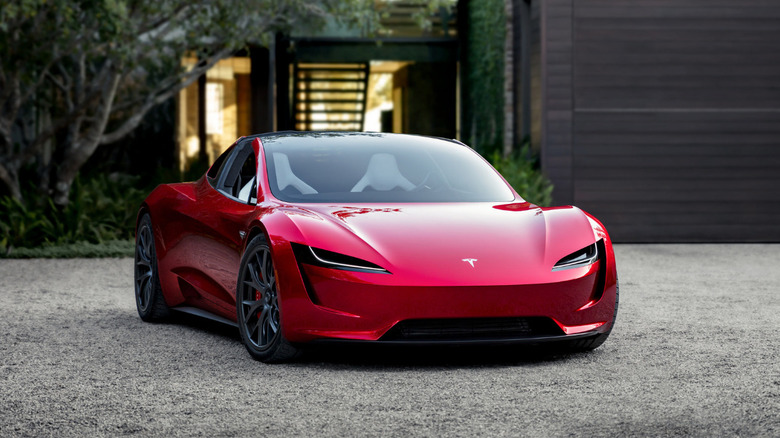 Red Tesla Roadster parked on a gravel driveway