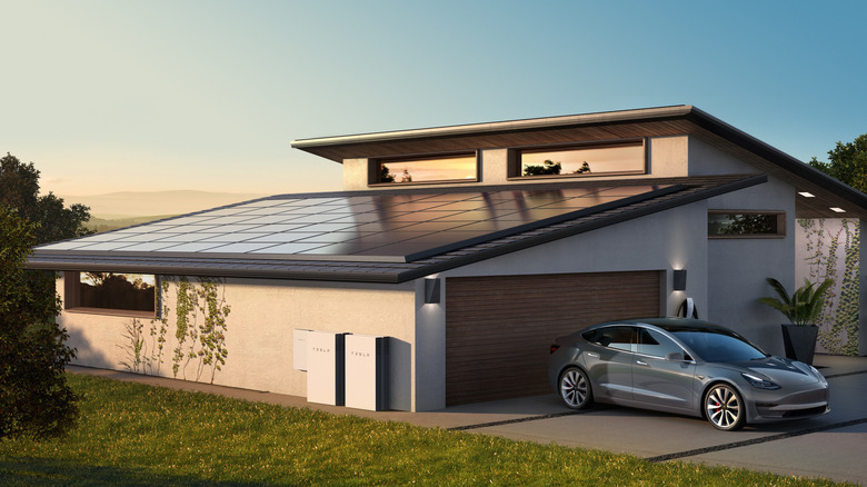 Tesla virtual power plant home on a clear, sunny day, with Tesla solar panels, a Tesla Powerwall, and a Tesla EV