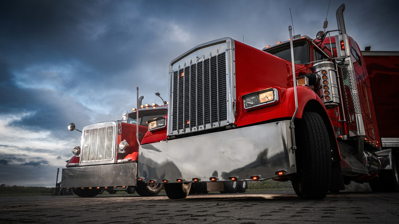 Two red semi trucks parked outside.