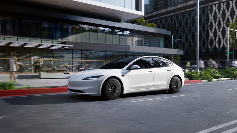 A white Tesla Model 3 Standard driving on an urban road