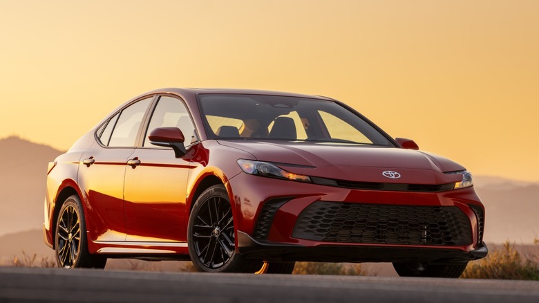 Red Toyota Camry parked on a road at sunset