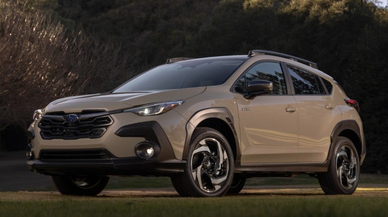 Beige Subaru Crosstrek Hybrid parked on grass with trees in the background