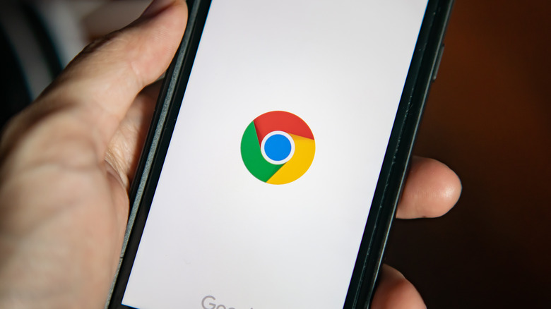 mão segurando o telefone com o logotipo do Chrome