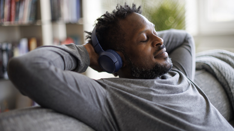 person relaxing on couch wearing headphones