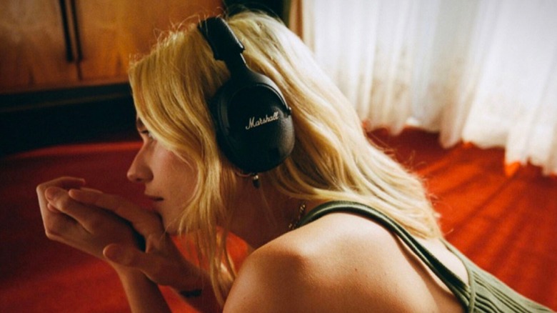 person laying on bed wearing Marshall Monitor II ANC headphones