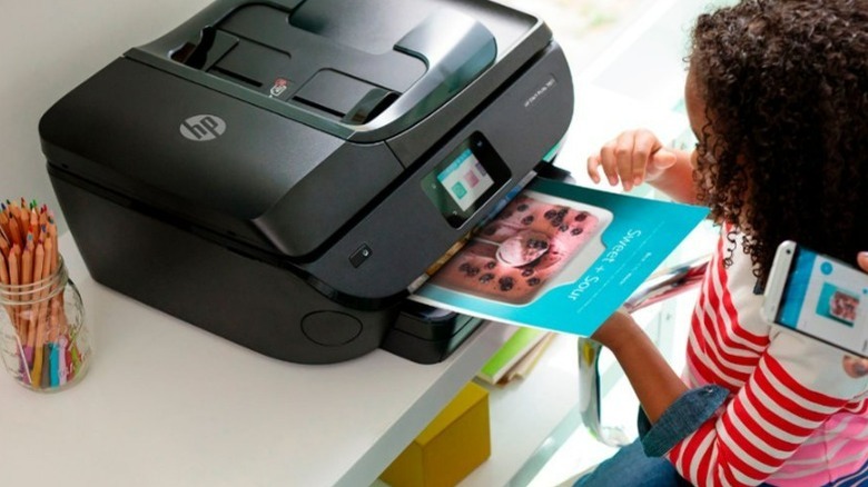 An HP Envy Photo 7855 printing out a sample photo of a young girl.