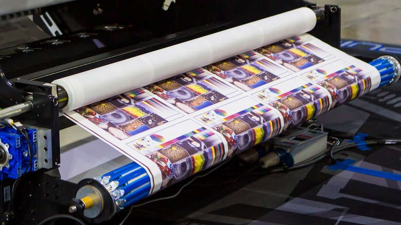 A high-tech dye-sublimation printer rolling sheets of paper. 