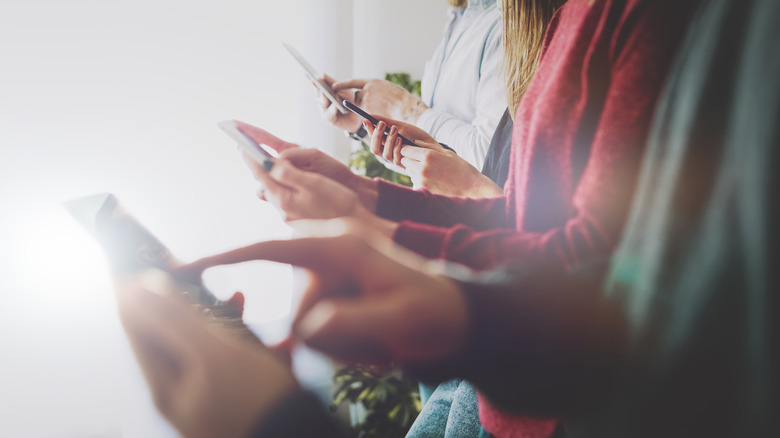 Many hands holding different smartphones