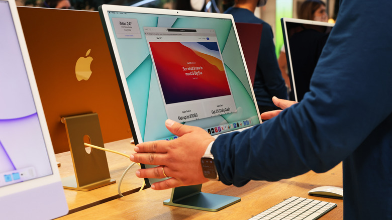 Apple iMac on display with a personn touching it