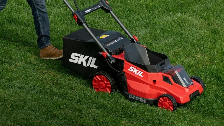 Landscaper pushing a Skil mower across a lawn