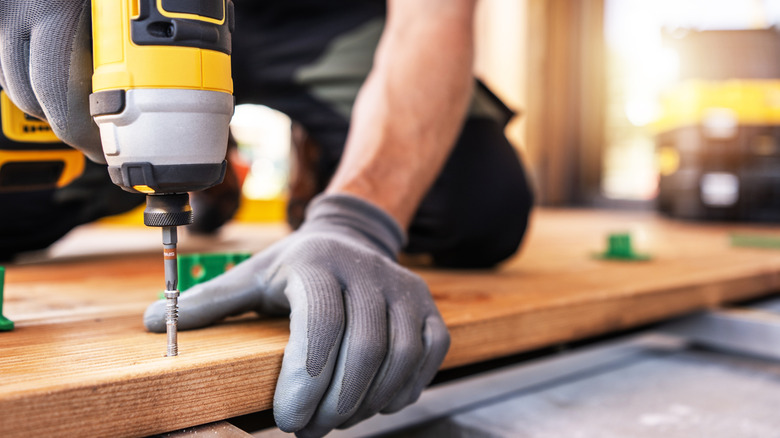 man in gloves using a cordless drill