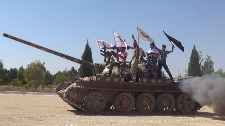 A T-54 Main Battle Tank with members of the the al-Tawhid Brigade standing on top while waving flags