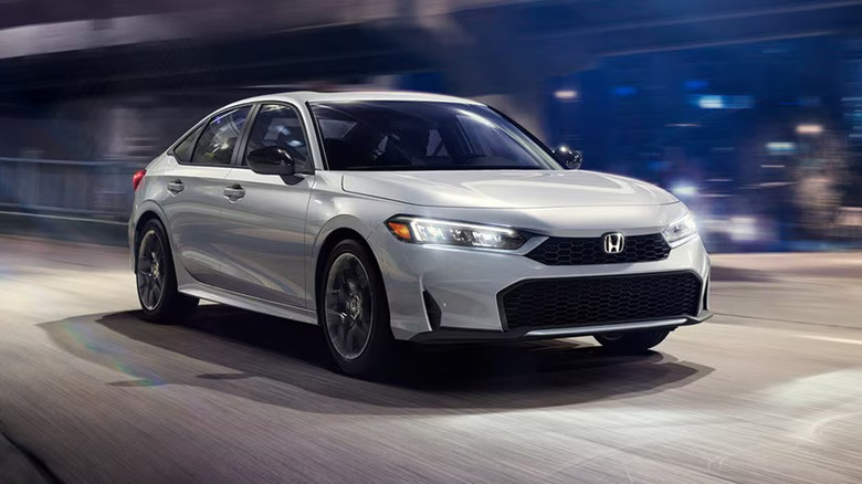 A 2026 Honda Civic Sedan finished here in the four-door variant in a white colorway, moving down a road.