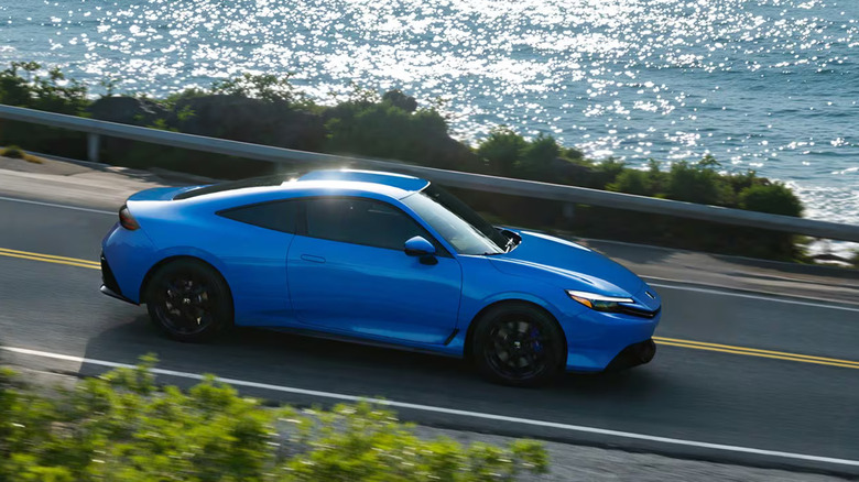 A 2026 Honda Prelude moving down a coastal stretch of road, pictured here in the "Boost Blue Pearl" color option.