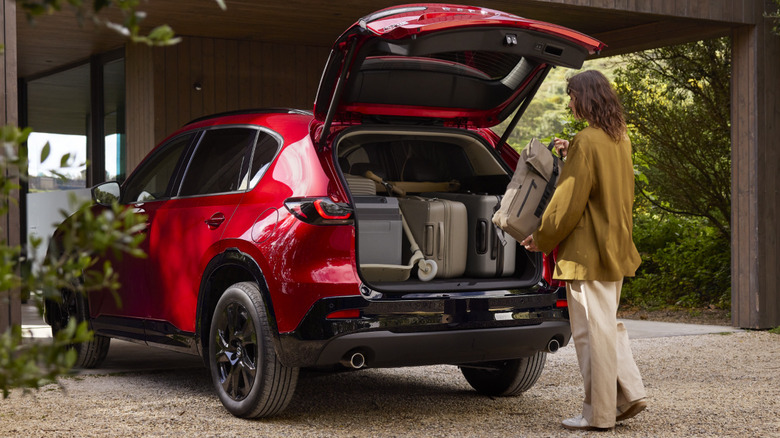 2026 Mazda CX-5 with the tailgate open, person loading another bag into the cargo area